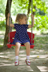 Adorable little girl having fun on a swing outdoor
