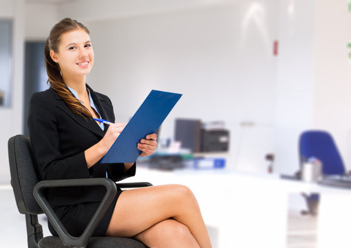 Businesswoman sitting on a chair and writing some documents