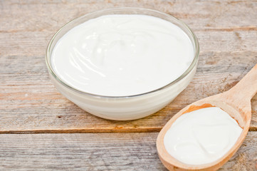 Fototapeta na wymiar sour cream in a glass bowl and wooden spoon