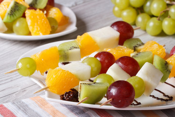 Fototapeta na wymiar Dessert of fresh fruit on skewers close-up. Horizontal