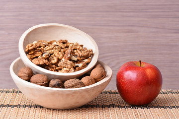 Wooden dishes with fruits, apple and nuts on bowl table