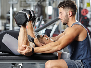 Personal instructor helping a man in the gym