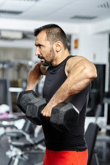 Fototapeta na wymiar Man doing shoulder workout in a gym