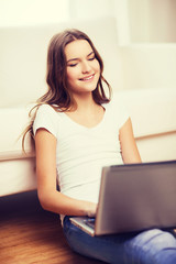 smiling teenage girl with laptop computer at home