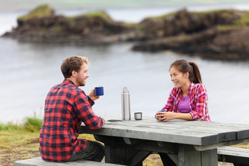 Camping couple sitting at table drinking coffee