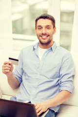 smiling man working with laptop and credit card