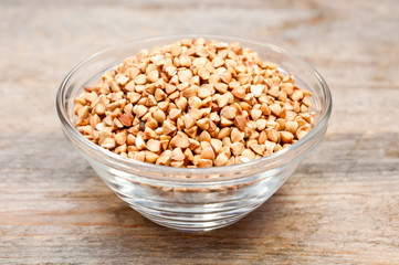 Dry buckwheat groats in a bowl on wooden table