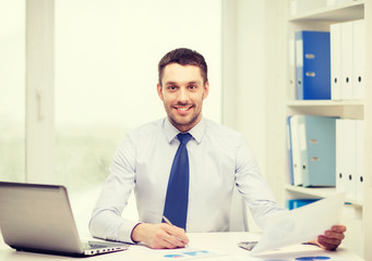 smiling businessman with laptop and documents