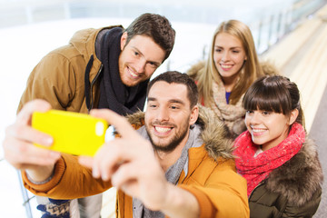 happy friends with smartphone on skating rink