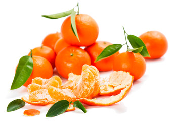 Fresh tangerine fruits with green leaves and slices.