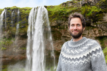 Man in Icelandic sweater by waterfall on Iceland