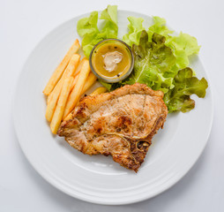 Pork steak with french fries and salad on a white background.