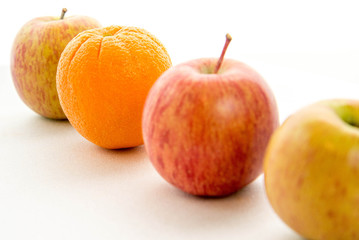 line of apples with one orange