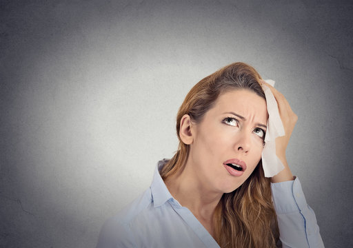 tired worried woman wipes sweat on her face grey background 