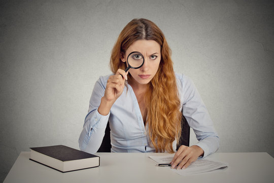 woman with glasses skeptically looking through magnifying glass - Powered by Adobe