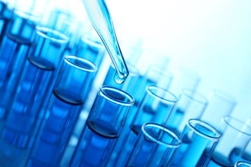 Pipette adding blue fluid to the one of test-tubes