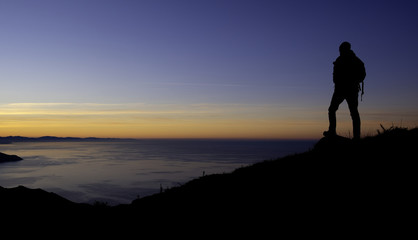 Man playing sports on the mountain with sunset and sea.