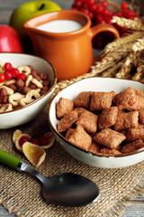 Various sweet cereals in ceramic bowls, fruits and jug with