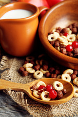 Various sweet cereals in bowl, fruits and jug with milk