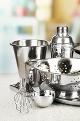 Stainless steel kitchenware on table, on light background