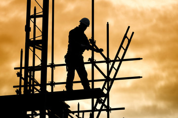 silhouette construction worker on scaffolding building site - obrazy, fototapety, plakaty