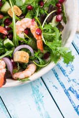 Healthy salad with seafood and pomegranade in rustic bowl