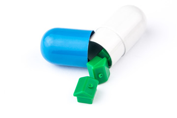 three small green houses are coming out from big pill