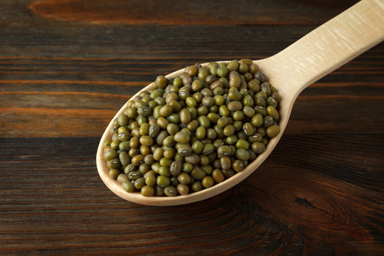 Mung beans in a wooden spoon on wood