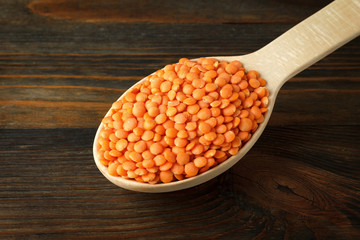 Red lentil in a wooden spoon on wood