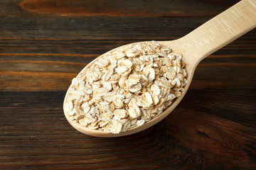 Rolled oats in a wooden spoon on wood