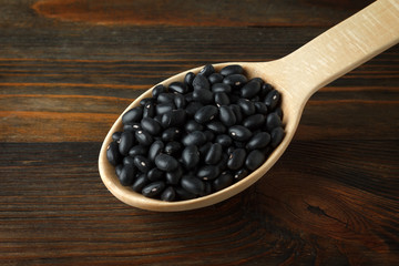 Black beans in a wooden spoon on wood