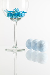 Glass of wine and golf equipments