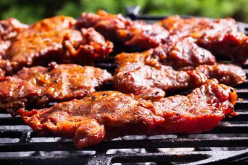 Grilling pork steaks on barbecue grill