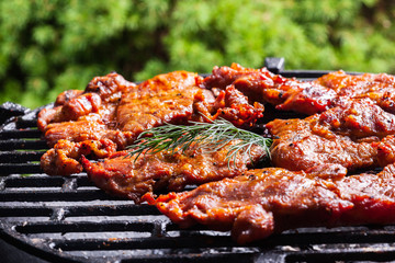 Grilling pork steaks on barbecue grill