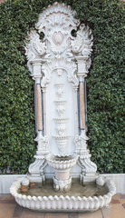 Ornate fountain by a hedge