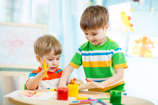 smiling kids play and paint at home or kindergarten or