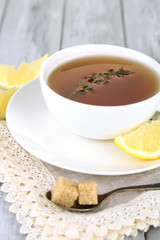 Cup of tasty herbal tea with thyme and lemon on wooden table