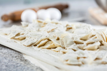 Flour And Raw Ravioli Pasta On Cutting Board