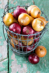 red and yellow onion in an iron basket on wooden surface
