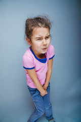 girl child badly wants the toilet on a gray background