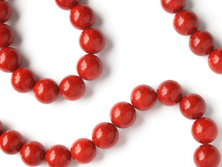 Glossy red coral beads on white background