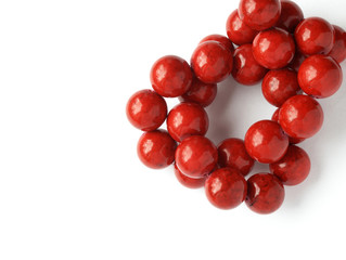 Glossy red coral beads knot on white background