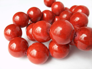 Glossy red coral beads knot on white background