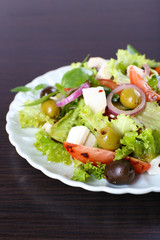 Greek salad in plate on wooden table background