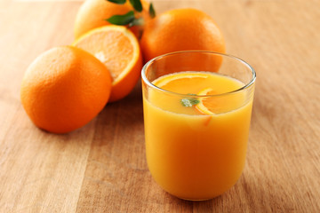 Glass of orange juice with slices on wooden table background