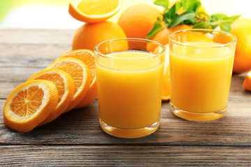 Glass of orange juice and slices on wooden table background