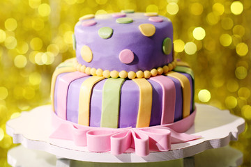 Delicious birthday cake on shiny yellow background