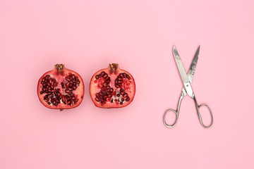 pomegranate cut in half and scissors on pink