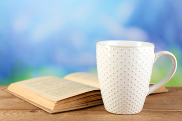 Cup of tea and book on table, on bright background
