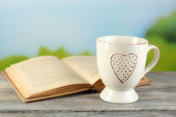 Cup and book on table, on bright background
